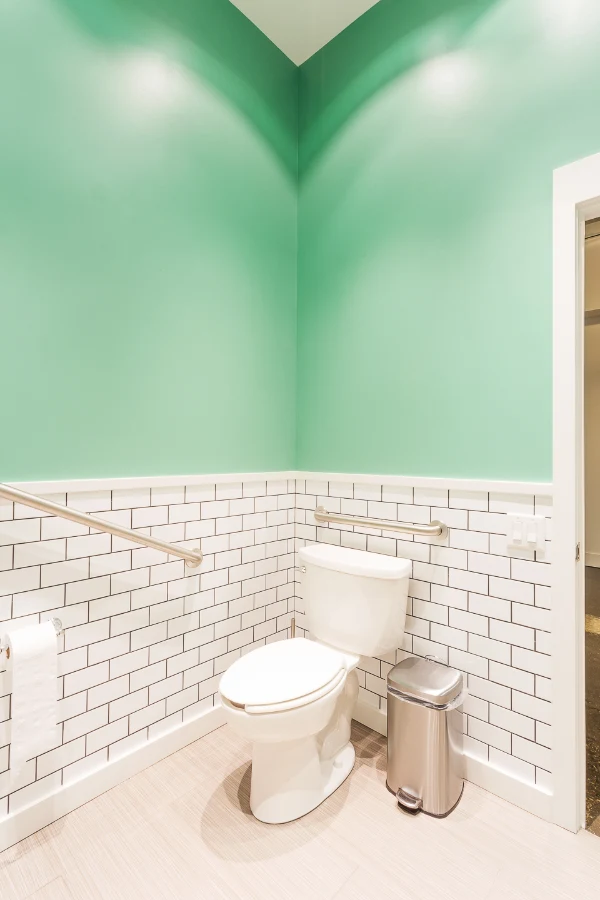 White subway tile and green walls in the washroom at See & Be Seen — Liberty Village