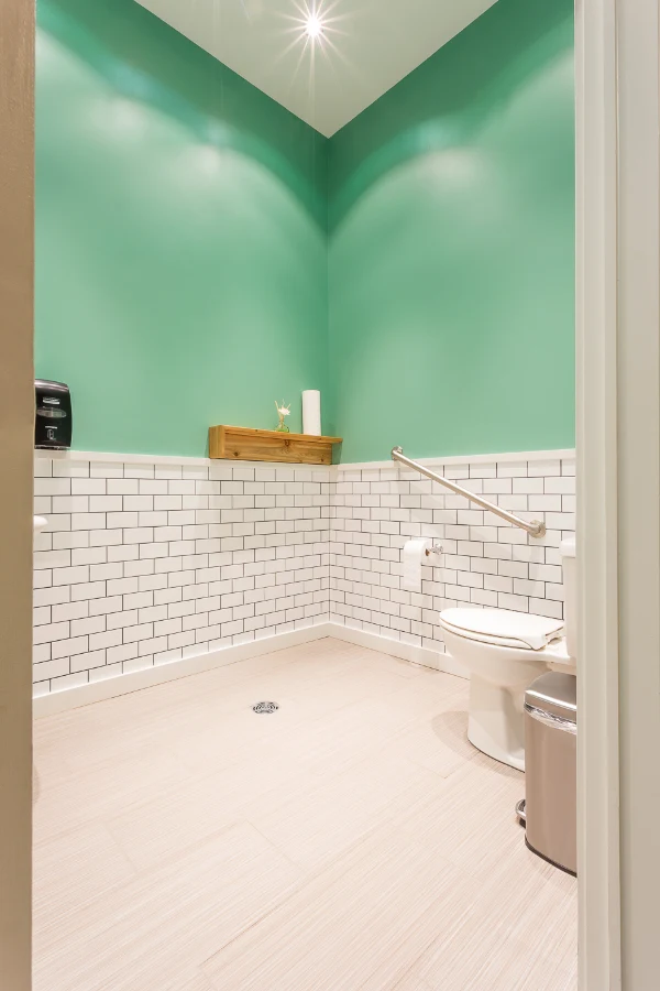 A washroom with green walls and white tile at See & Be Seen — Liberty Village
